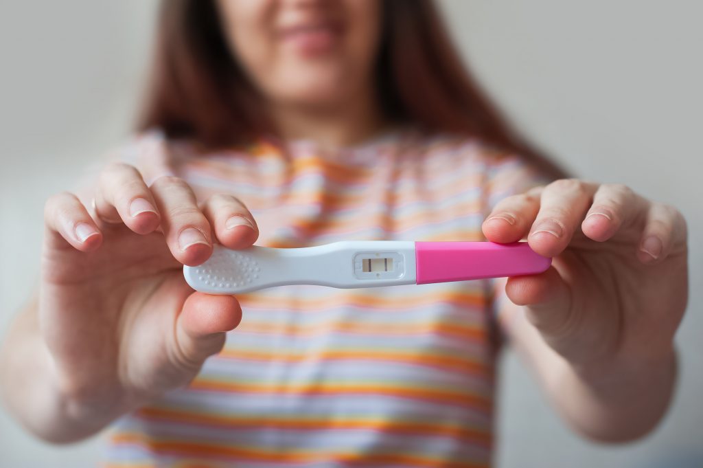 Positive pregnancy test in hands close up..